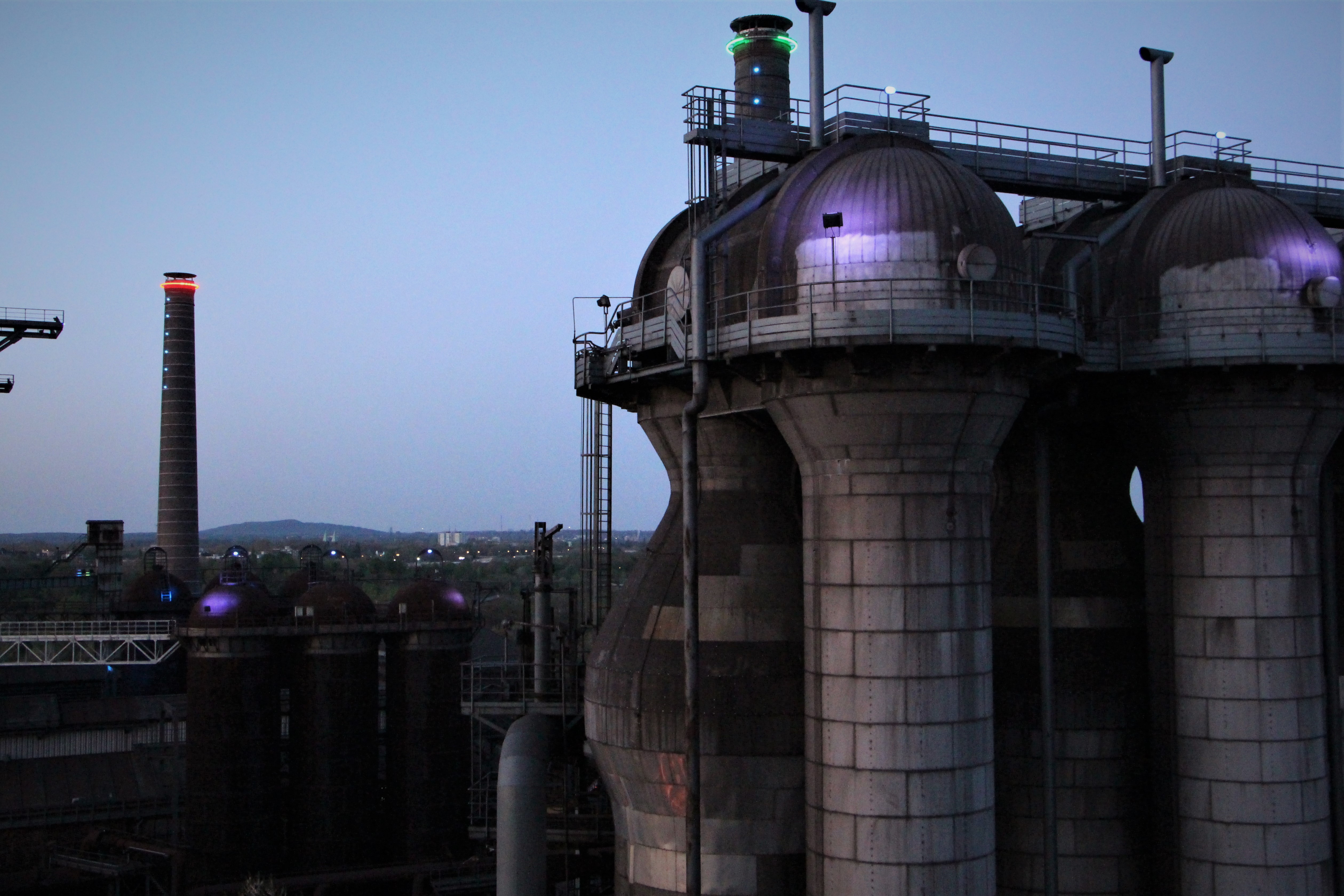 Neon lights color the factory as the sun begins to go down